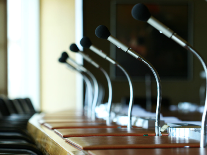 A long desk area with individual microphones installed.