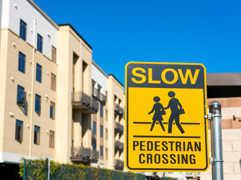 A sign alerts drivers to slow down for a pedestrian crossing.