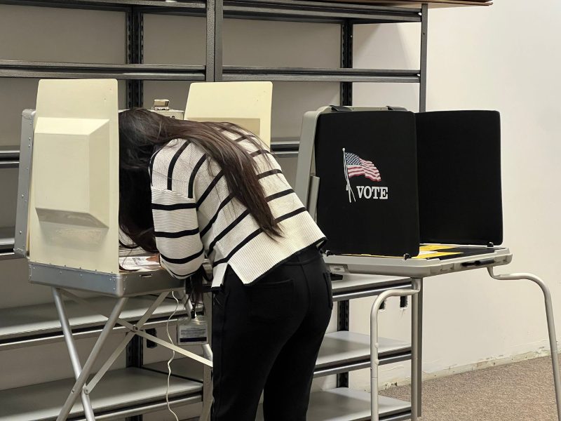 A photo of a person casting a ballot at a mock vote center.