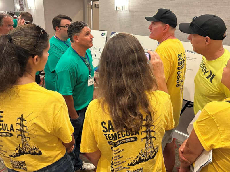 A group of people in yellow Save Temecula shirts talking with SDG&E employees in teal Golden Pacific Powerlink shirts.