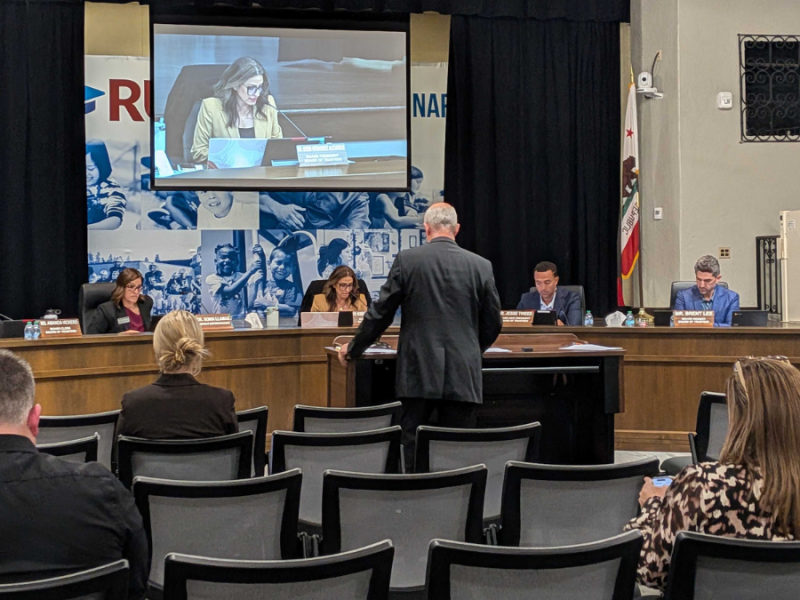 A person presents an agenda item to the RUSD board.